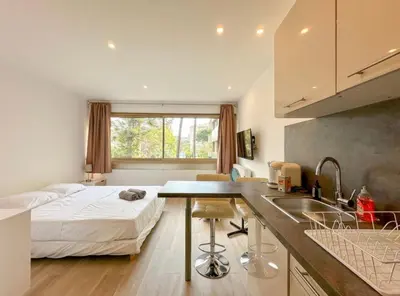 a bedroom with a bed and a kitchen with a sink at Studio Moderne Cannes - Parking - Proche de la plage in Cannes