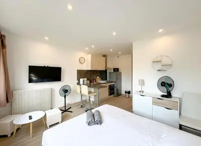 a bedroom with a white bed and a kitchen at Studio Moderne Cannes - Parking - Proche de la plage in Cannes