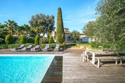 a pool with chairs and a table and a house at Villa Grand Largue - vue mer 180° in Cannes