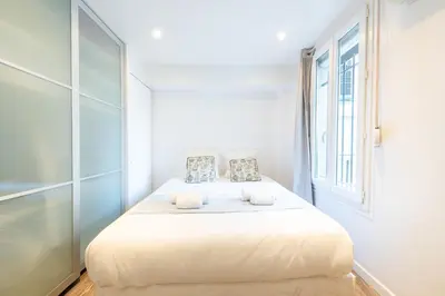 a white bed in a room with a window at 1-Br Apartment in Cannes Walk to the Beach in Cannes