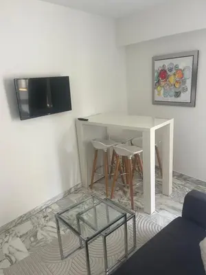 a white table with stools and a tv on a wall at Studio meublé, les tambourins in Cannes