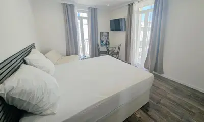 a large white bed in a bedroom with windows at Ref PINSON in Cannes