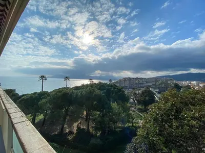 a view of the ocean with palm trees and buildings at Luxury 1 Bed Apt Seafront Escape in Cannes in Cannes