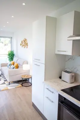 a kitchen with white cabinets and a white couch at Luxury 1 Bed Apt Seafront Escape in Cannes in Cannes
