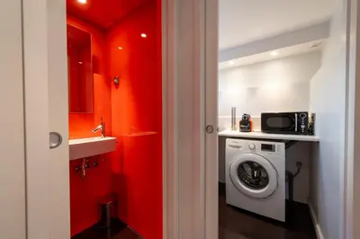 a bathroom with red walls and a washing machine at 1-Br 75m Duplex with Pool in Cannes