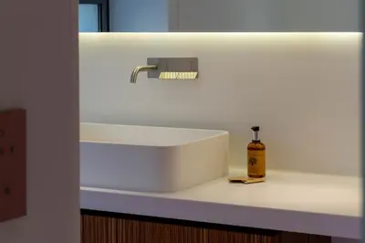 a white sink in a bathroom with a bottle of soap at 1-Br 75m Duplex with Pool in Cannes