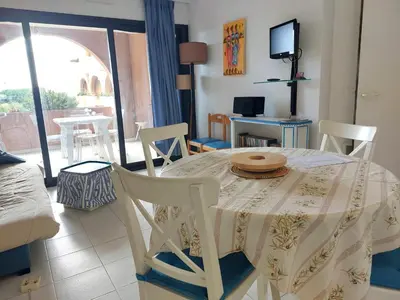 a dining room with a table and chairs and a tv at CARIBOU T2 piscine - Axelle Loc'Appart in Cannes