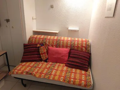 a couch with three pillows on it in a room at CARIBOU T2 piscine - Axelle Loc'Appart in Cannes