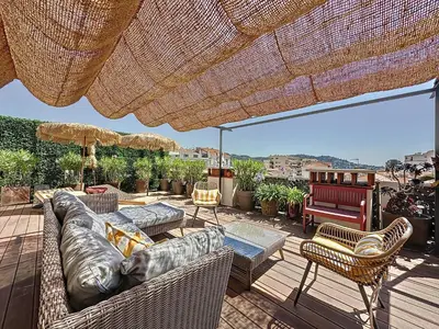 a patio with a couch and chairs and an umbrella at Intuition Rooftop vaste terrasse in Cannes
