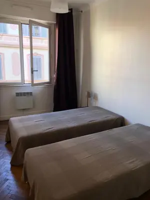 two beds in a room with a window at merimée 4G in Cannes