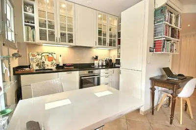 a kitchen with white cabinets and a table with a laptop at magnifique 2 pièces parc de la croisette in Cannes