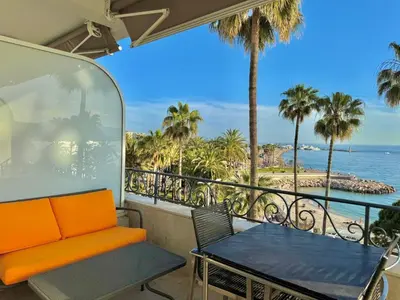 a balcony with a bench and a table and the ocean at 1-bedroom apartment with balcony and sea view on La Croisette in Cannes