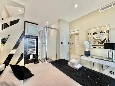 a bedroom with a large bed and a shower at 1-bedroom apartment with balcony and sea view on La Croisette in Cannes