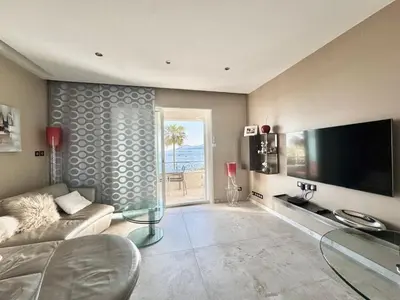 a living room with a couch and a large television at 1-bedroom apartment with balcony and sea view on La Croisette in Cannes