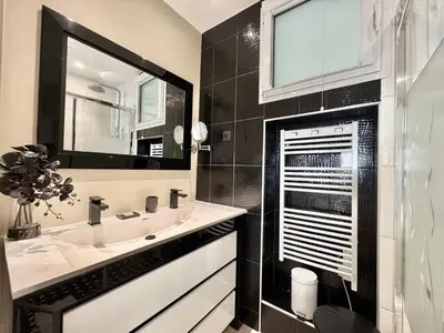 a black and white bathroom with a sink and a mirror at 1-bedroom apartment with balcony and sea view on La Croisette in Cannes
