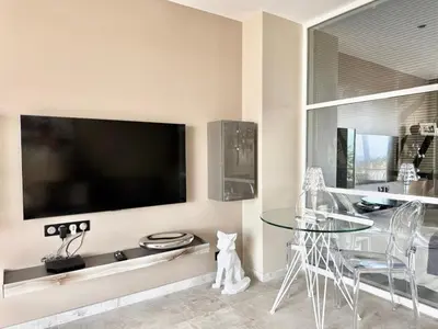 a living room with a glass table and a large tv at 1-bedroom apartment with balcony and sea view on La Croisette in Cannes