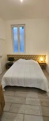 a large white bed in a room with two windows at F3 ground floor, Hypercentre 2 min from Palace in Cannes
