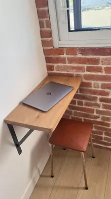 a laptop sitting on a wooden table next to a brick wall at Studio 3étoiles à 10 min du Centre - Calme in Cannes