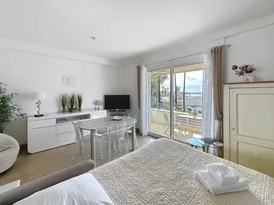 a bedroom with a bed and a table and a balcony at 1-bedroom apartment with sea view on La Croisette in Cannes