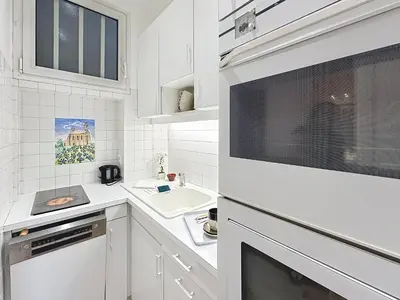 a white kitchen with a sink and a microwave at 1-bedroom apartment with sea view on La Croisette in Cannes