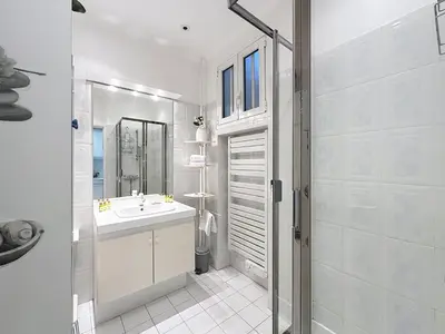a white bathroom with a sink and a mirror at 1-bedroom apartment with sea view on La Croisette in Cannes