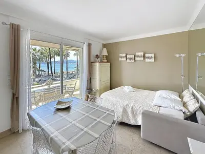 a bedroom with a bed and a table and a balcony at 1-bedroom apartment with sea view on La Croisette in Cannes