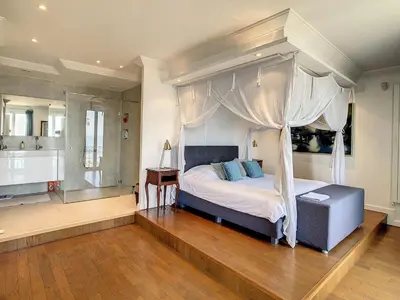 a bedroom with a canopy bed and a bathroom at Pura Vida in Cannes