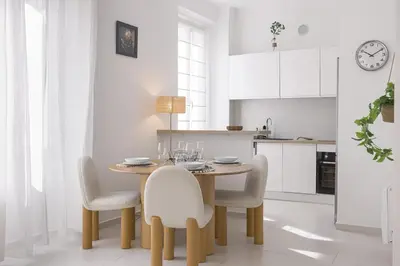 a white kitchen with a wooden table and chairs at Josi - 2 chambres, central, 10mn du Palais&Plages, neuf, clim in Cannes