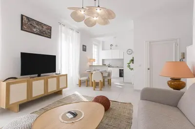 a living room with a tv and a couch and a table at Josi - 2 chambres, central, 10mn du Palais&Plages, neuf, clim in Cannes