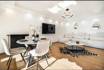 a living room with a white couch and a table and chairs at Appartement haut standing - Luxury apartment - Cannes- Croisette- Centre ville- Vue Tennis -Vue Piscine -Parking privé - Terrasse- Plage in Cannes