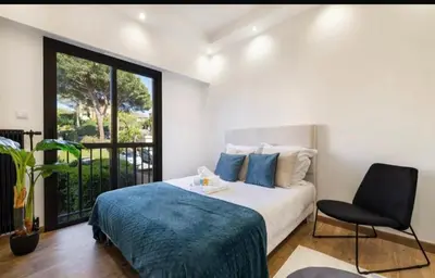 a bedroom with a bed and a chair and a window at Appartement haut standing - Luxury apartment - Cannes- Croisette- Centre ville- Vue Tennis -Vue Piscine -Parking privé - Terrasse- Plage in Cannes