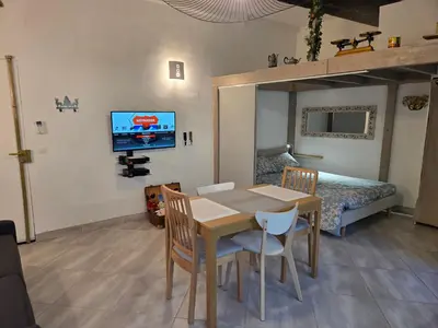 a dining room with a table and a bed and a television at Meynadier 66 - Appartement Très Calme avec Cour Privative, Plage, Gare, Palais à 300m in Cannes