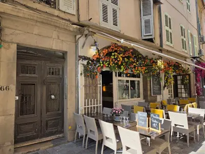 a restaurant with a table and chairs in front of a building at Meynadier 66 - Appartement Très Calme avec Cour Privative, Plage, Gare, Palais à 300m in Cannes