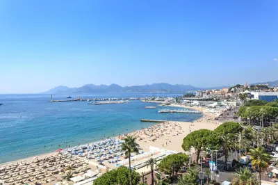 a beach with people and umbrellas and the ocean at Marlyn in Cannes