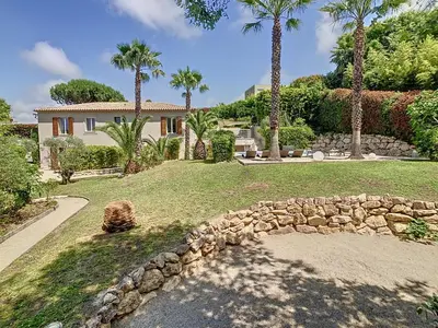 a house with palm trees and a stone wall at Villa Bamboo in Cannes