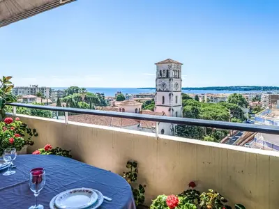 a balcony with a table and a clock tower at Apartment Le Katia-2 by Interhome in Cannes