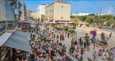 a crowd of people on a city street with a ferris wheel at Aparthotel Seaside Cannes Festival Suite in Cannes