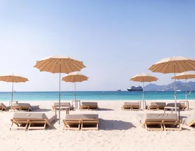 a beach with chairs and umbrellas and the ocean at Aparthotel Seaside Cannes Festival Suite in Cannes