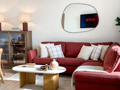 a living room with a red couch and a round mirror at Cannes centre - 10mn Palais, Croisette, Plage - CY in Cannes