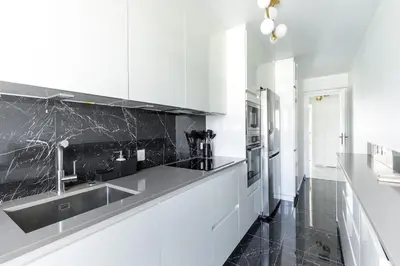 a kitchen with white cabinets and a black counter top at Luxurious Apartment with Sea and Carlton View in Cannes