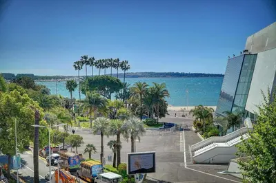 a view of a parking lot with palm trees and the ocean at REF 1392 - Cannes palais des festivals apartment for rent in Cannes