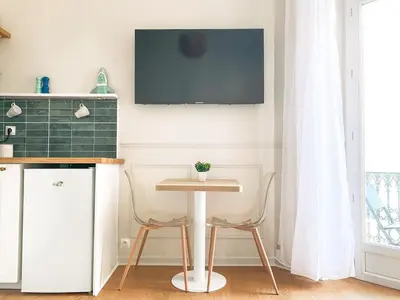 a kitchen with a table and two chairs and a tv at Charmant 2P avec Balcon, Proche Centre in Cannes