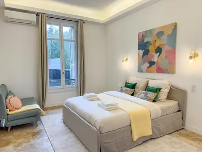 a bedroom with a large bed and a chair at Grand appartement rénové - Jardin et Parking - CZ in Cannes