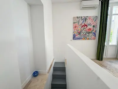 a staircase in a white room with a painting on the wall at Grand appartement rénové - Jardin et Parking - CZ in Cannes