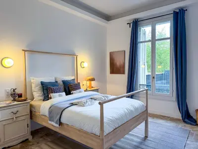 a bedroom with a bed with blue curtains and a window at Bel appartement rénové - Jardin et Parking - DA in Cannes