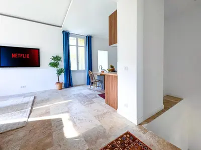 a living room with a tv on a wall at Bel appartement rénové - Jardin et Parking - DA in Cannes