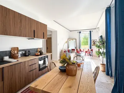 a kitchen and dining room with a wooden table at Bel appartement rénové - Jardin et Parking - DA in Cannes