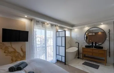 a bedroom with a tub and a sink and a mirror at Les YUCCAS - 2 pièces Suquet Parking Vue Mer pour 4 personnes in Cannes