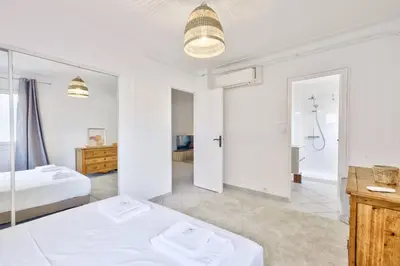 a white bedroom with two beds and a bathroom at T3 proche de la Croisette et Palais des Festivals in Cannes