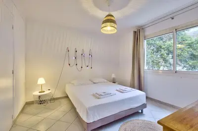 a white bedroom with a bed and a window at T3 proche de la Croisette et Palais des Festivals in Cannes